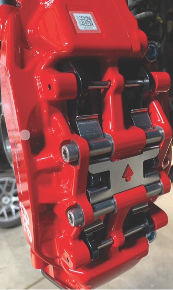 AP Racing caliper with the pads, retaining spring, and pins visible